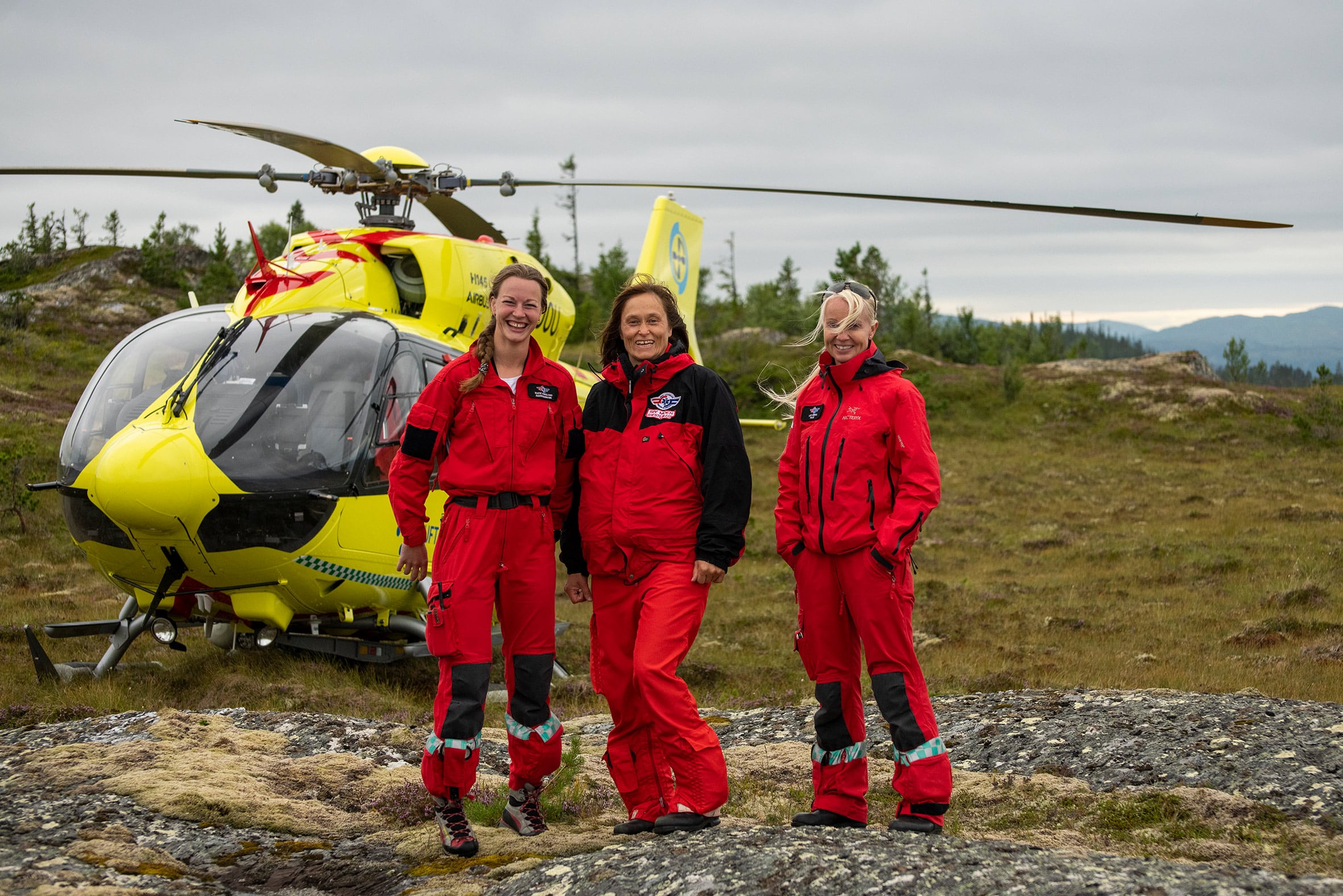 Tre kvinner i crewet foran legehelikopteret