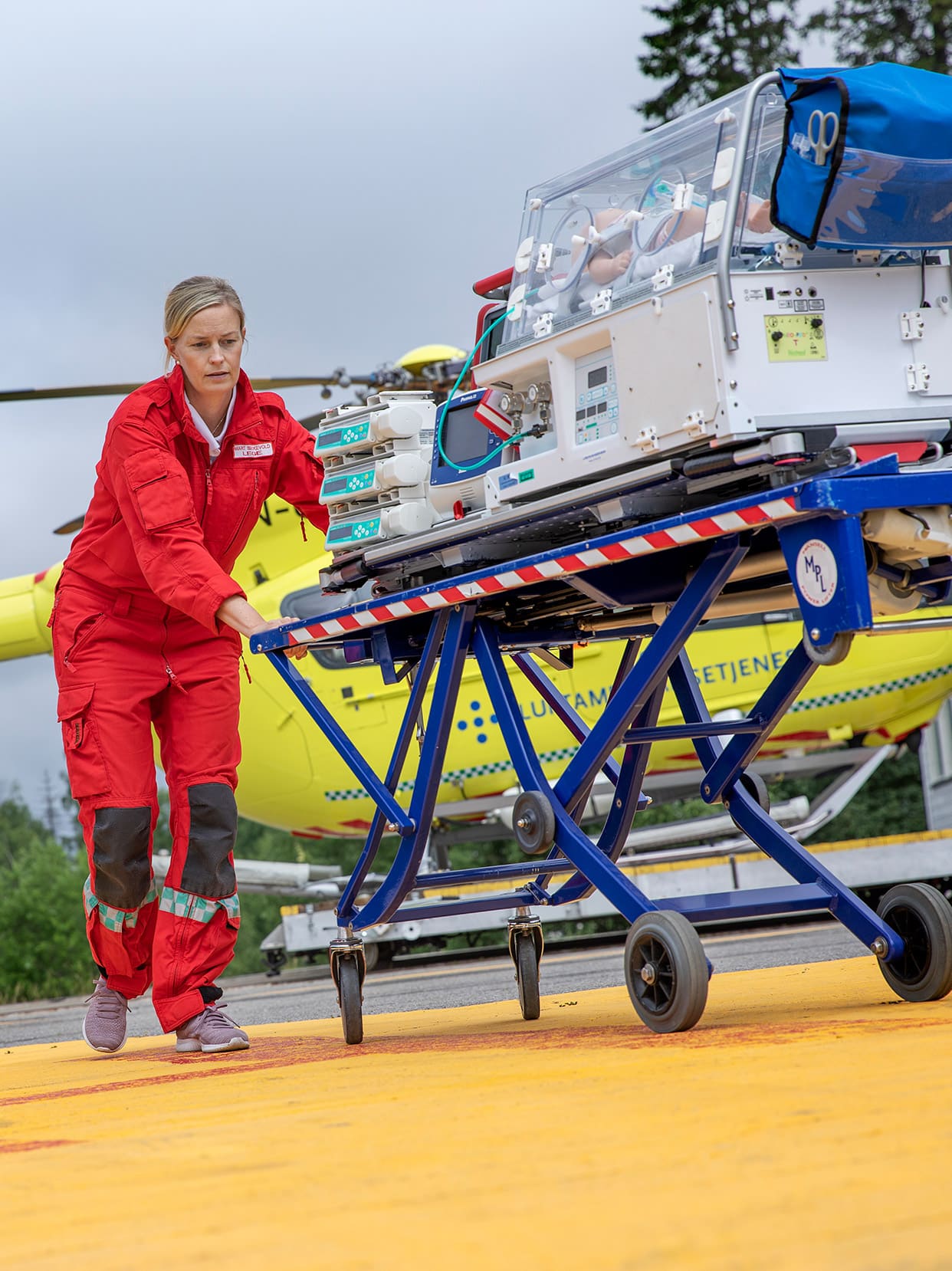 Forsker Marit Bekkevold transporterer kuvøse for nyfødt fra helikopter.