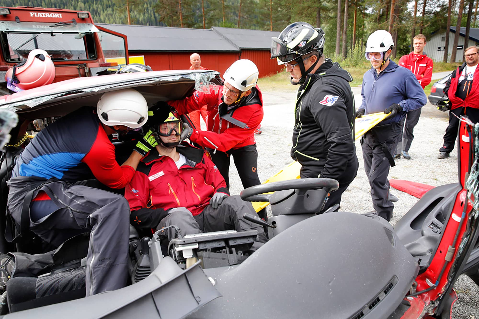 Lege og redningsmann evakuerer pasient fra bilvrak under øvelse i hurtigfrigjøring. Blir vurdert av øvelsesleder.