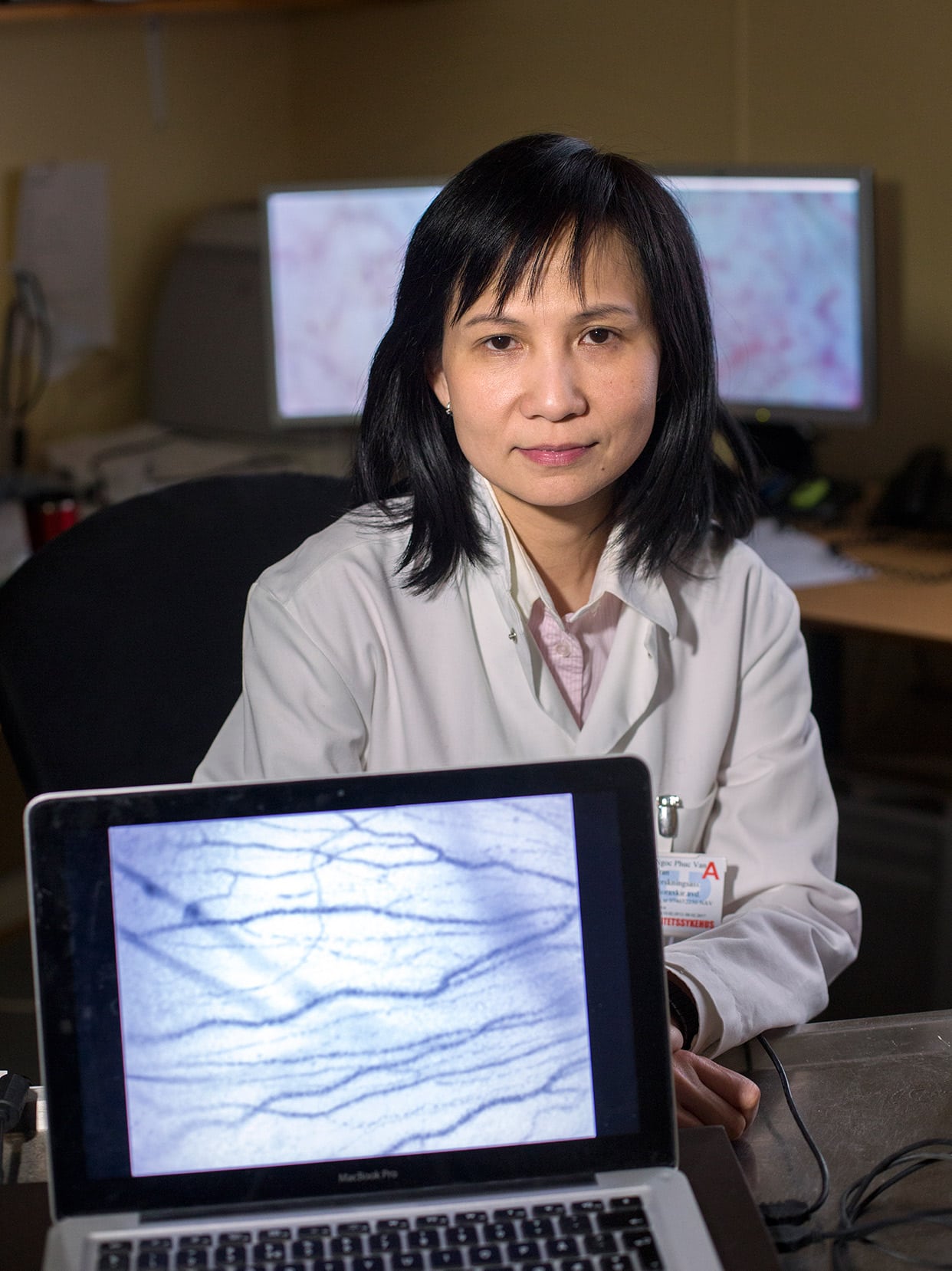 Forsker Van Tran Ngoc Phuc i legefrakk bak bærbar datamaskin med grafer