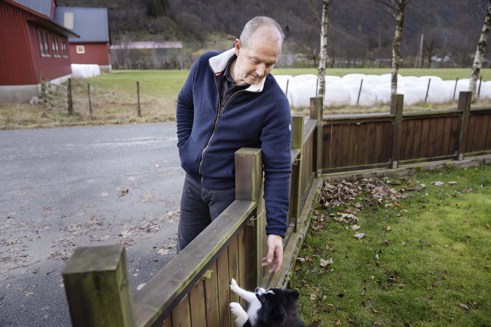 Oddmund Haaland hilser på en hund ved et gjerde.