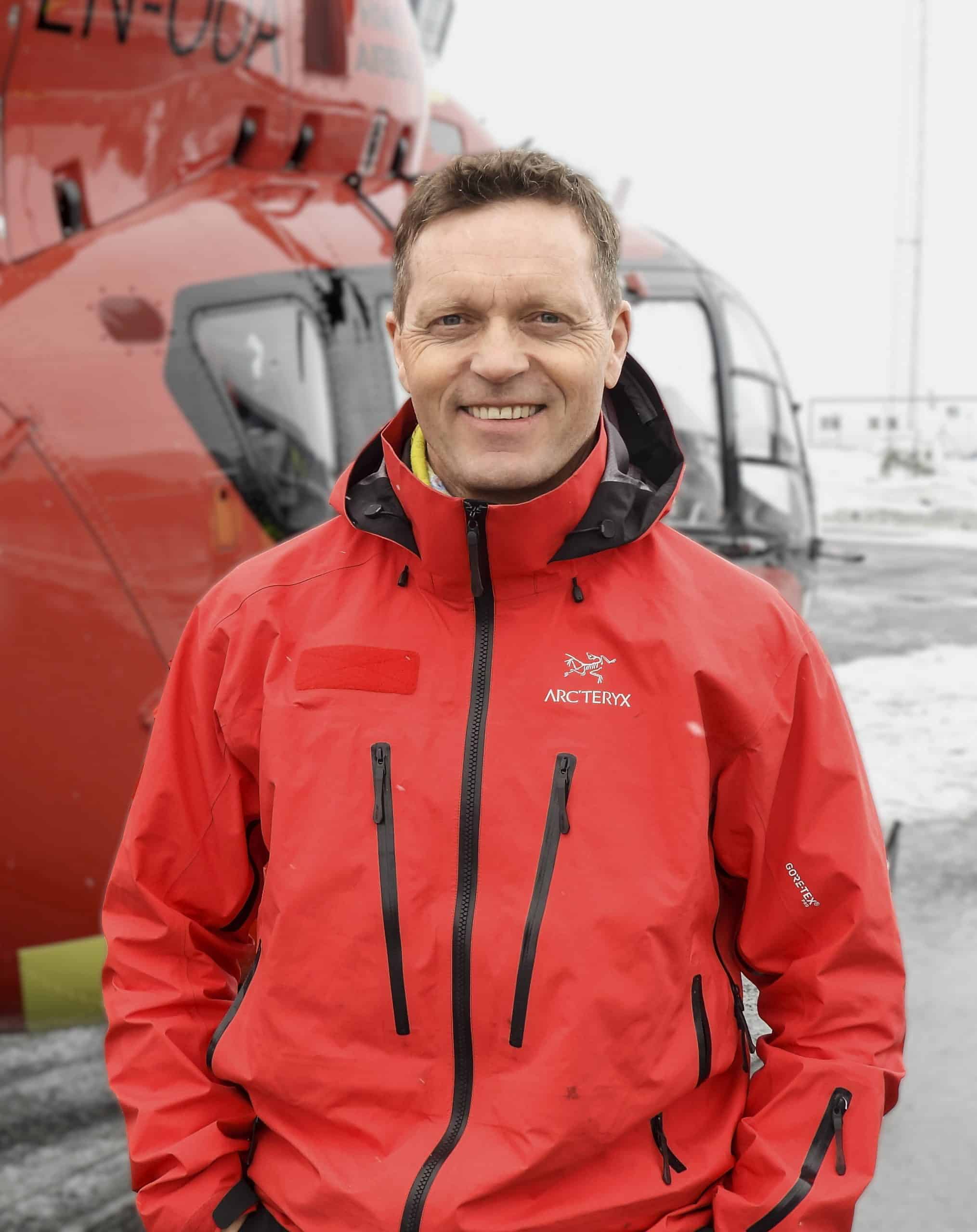 Portrett av pilot Lars Amdal foran helikopter