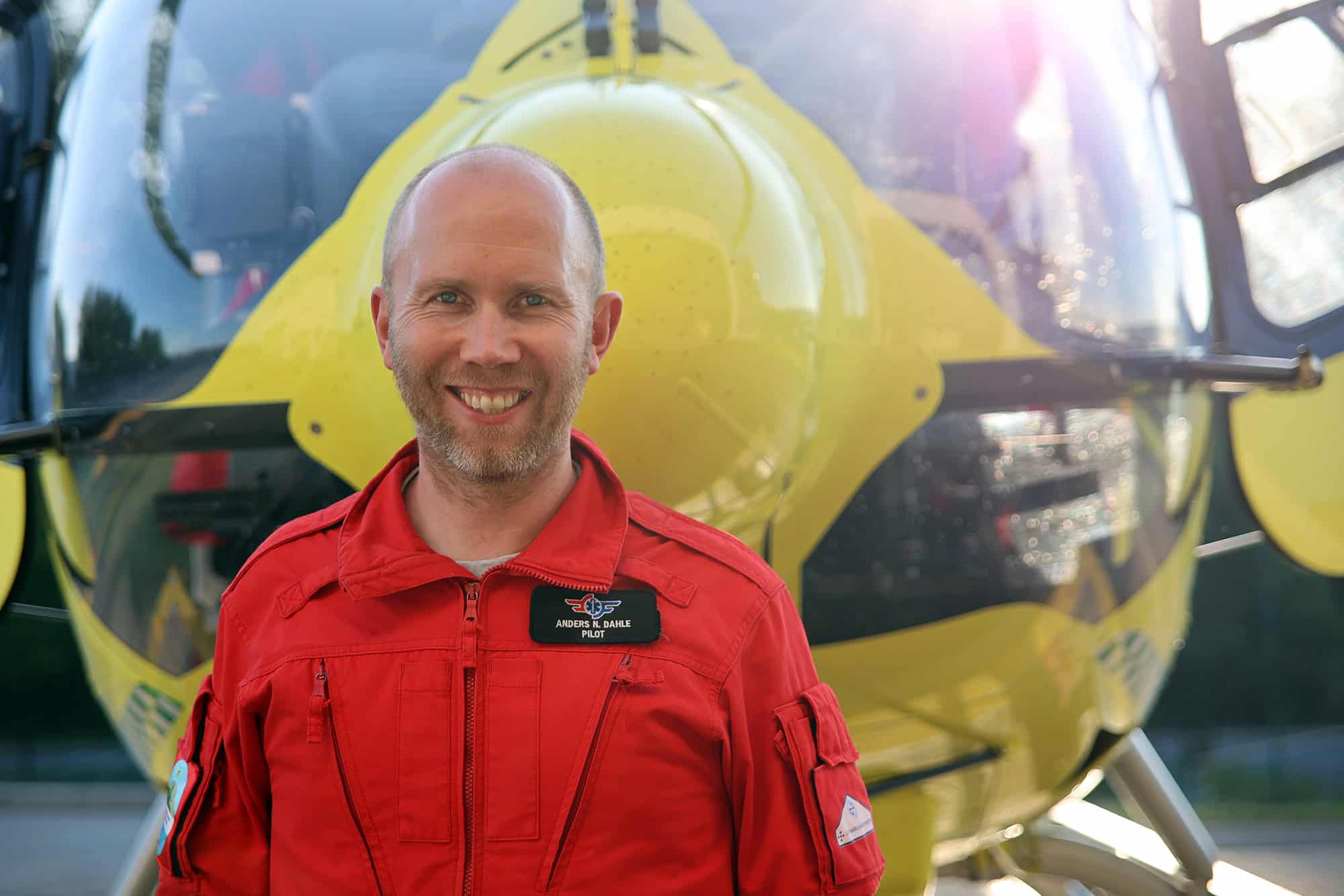 Bilde av Anders Nordgaard Dahle foran gult legehelikopter. Han hadde pilotvakt da Marit fikk hjerteinfarkt. 