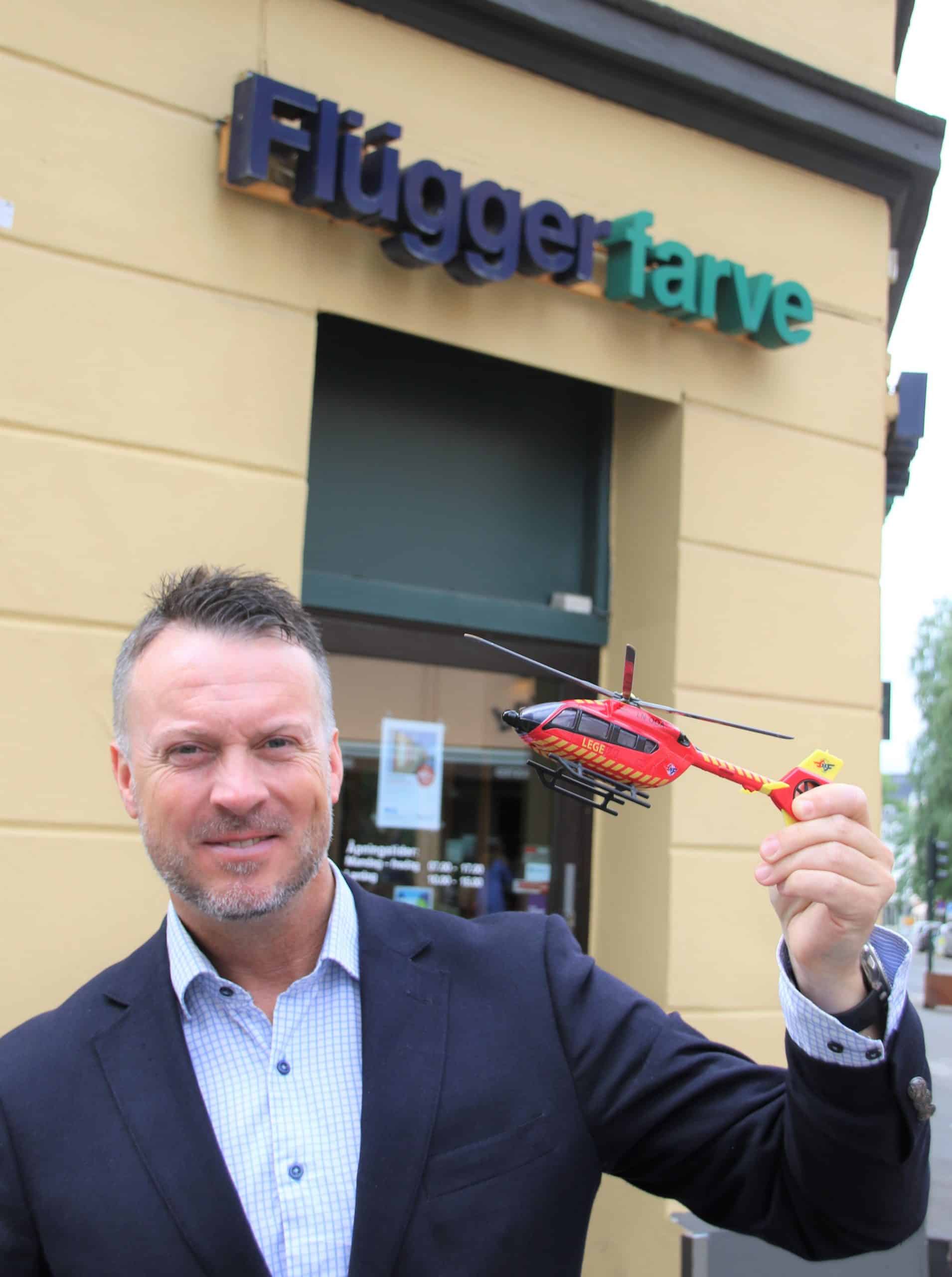 Steffen Kristian Eide fra Flügger Norge holder en helikoptermodell foran en av butikkene