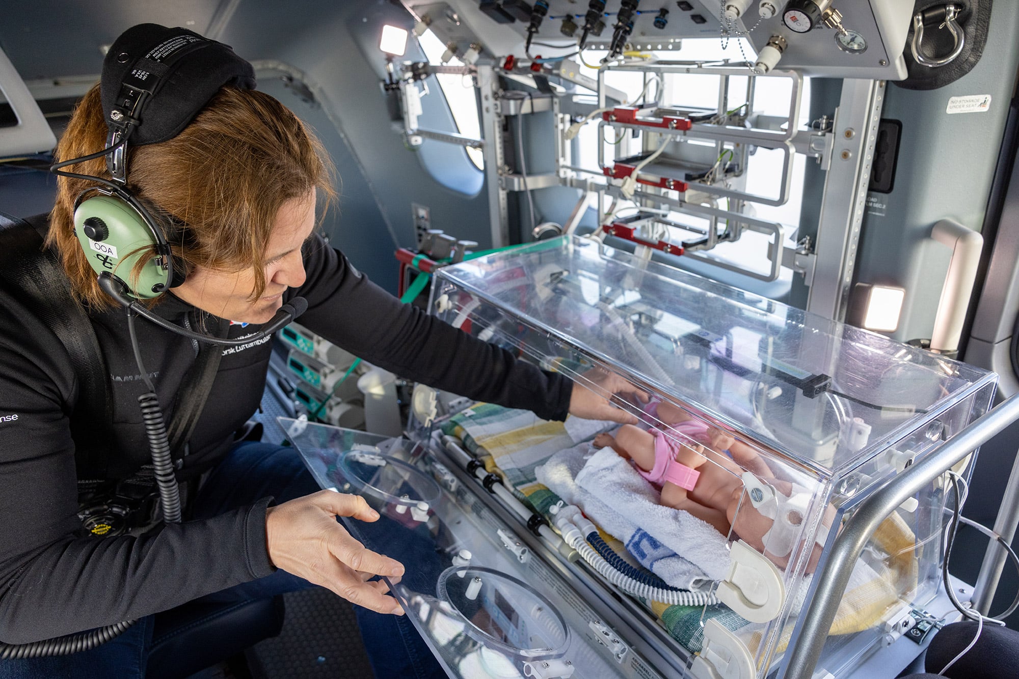 Doktorgradsstipendiat i helikopterkabin under øvelse med spedbarn i kuvøse