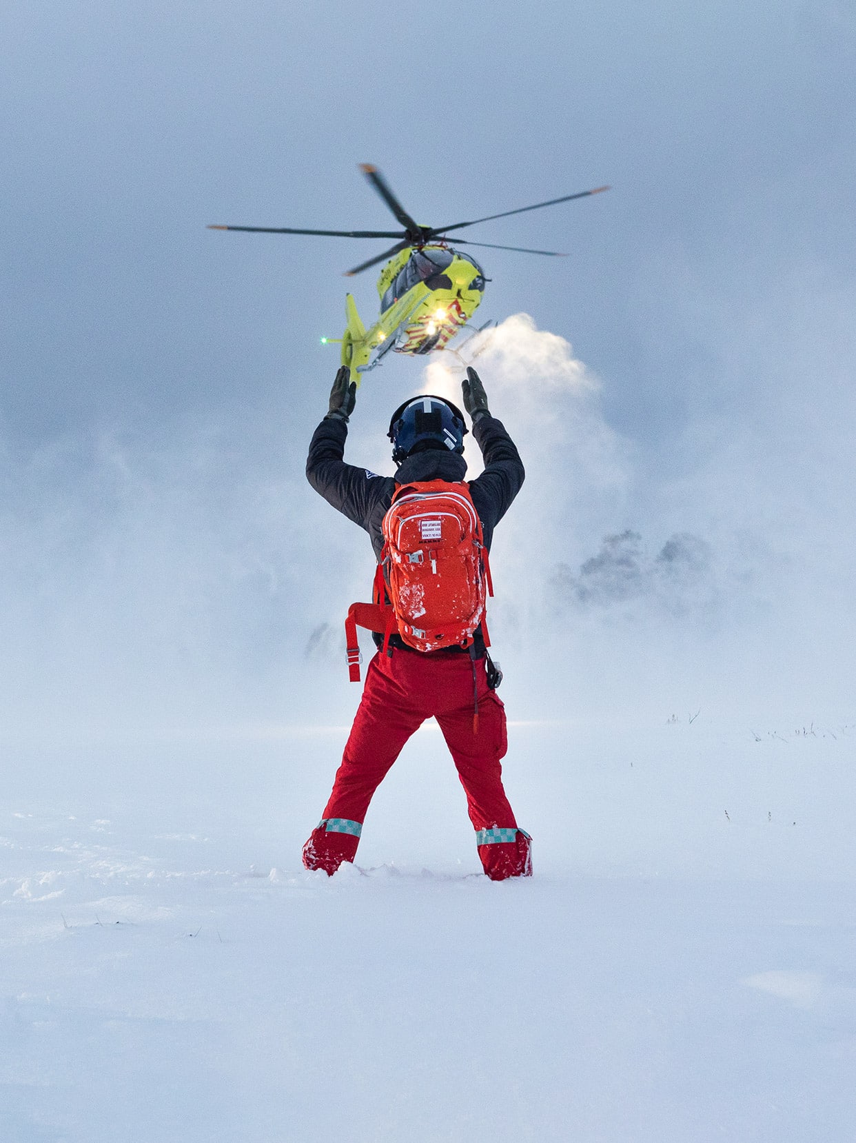Redningsmann signaliserer til et helikopter i snølandskap