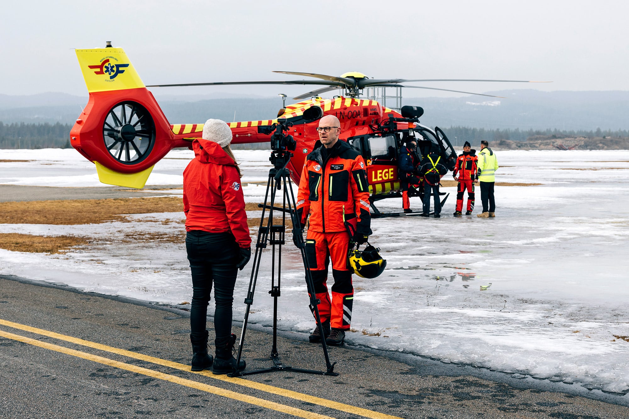 Pilot blir intervjuet og filmet med helikopter bak seg 