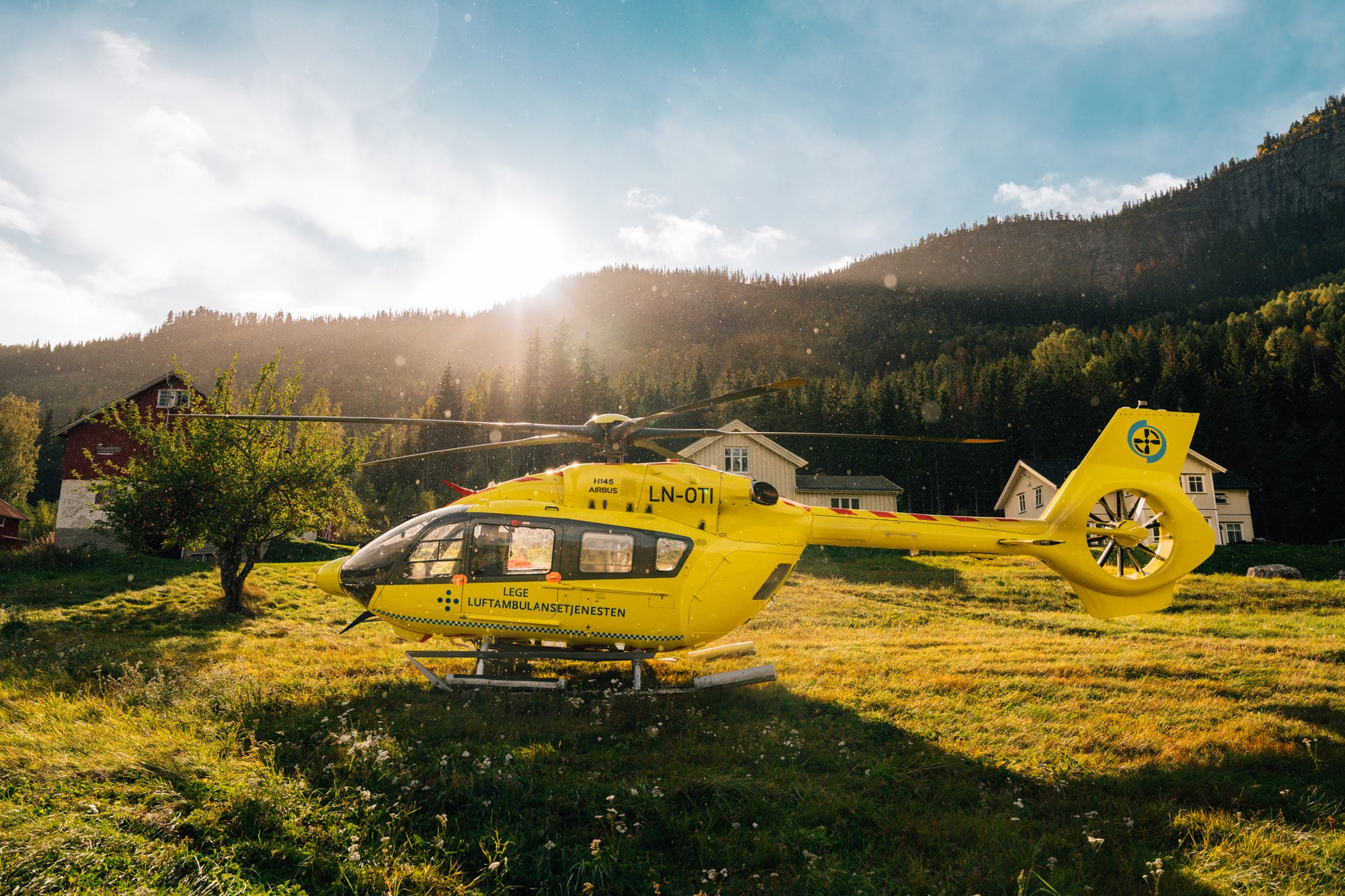 Gult helikopter fra Norsk Luftambulanse landet i gress. Bildet er tatt på Stavn.