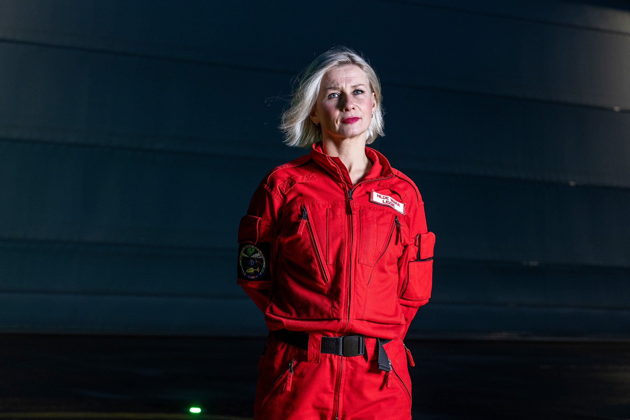 Portrett av sjeflege Hilde Wara i rød dress foran helikopterbase.