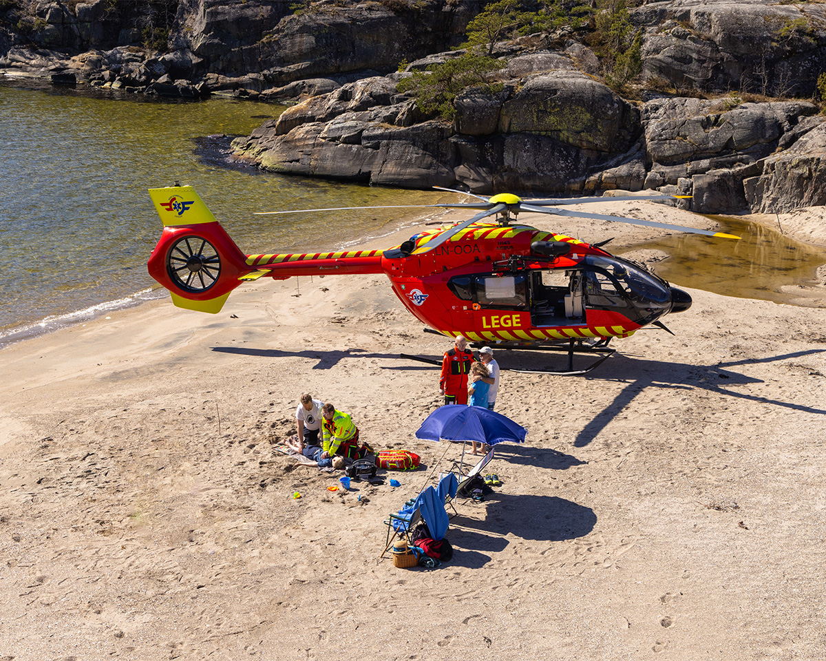 Helikopter-crew hjelper en ung gutt på stranden.