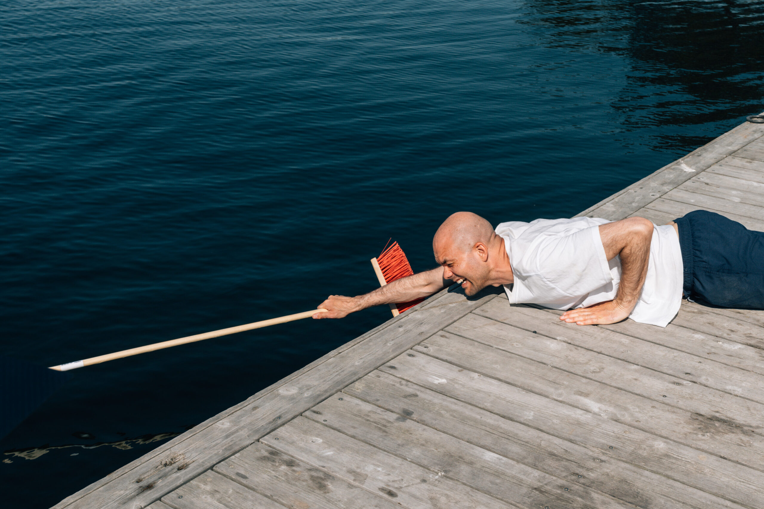 Lars Berrum rekker en kost ut i vannet til en person som er i ferd med å drukne. Bilde tatt i forbindelse med filming av opplysningsfilm om drukning.