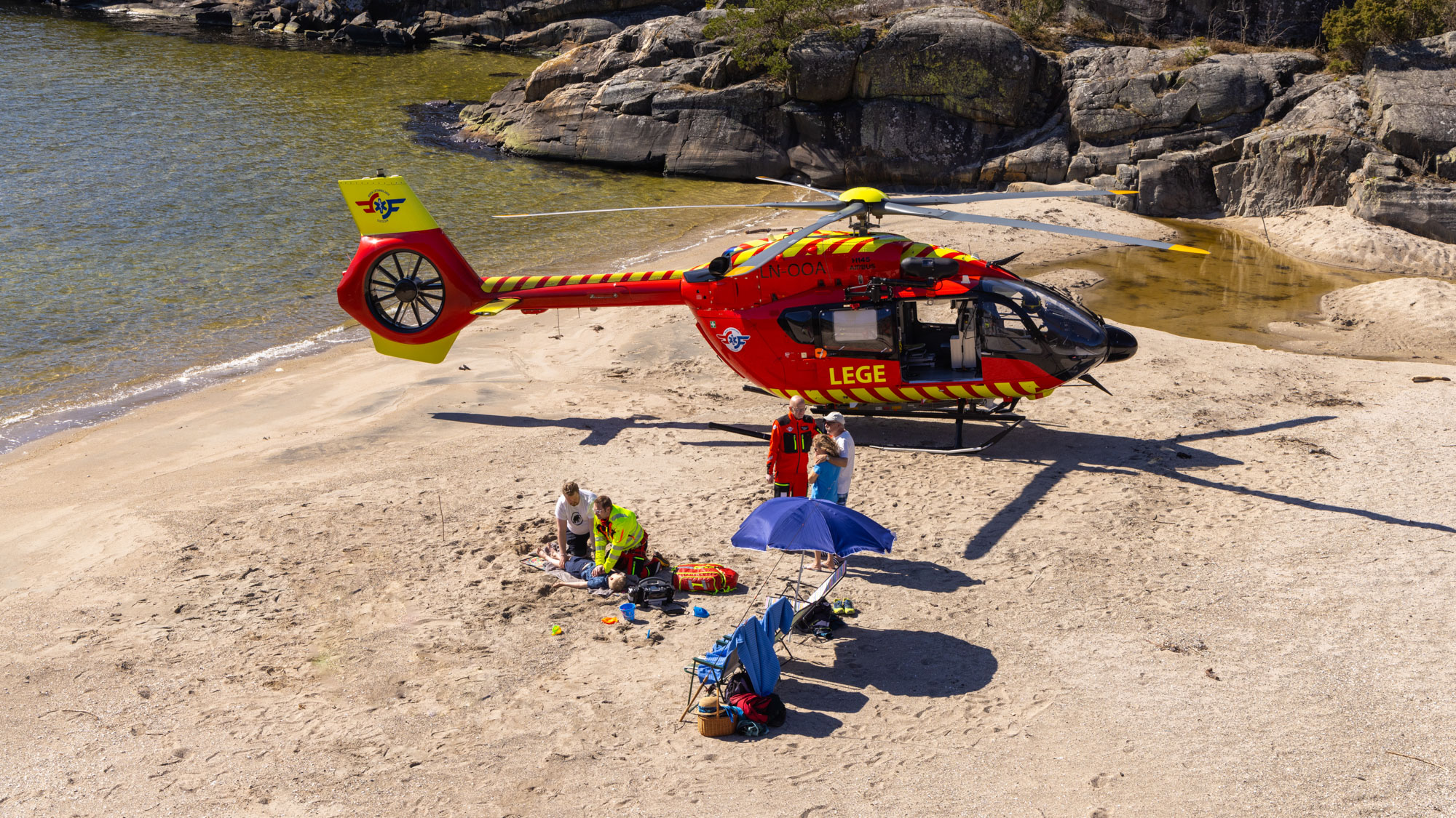 Utviklingshelikopter og crew hjelper barn på en strand.