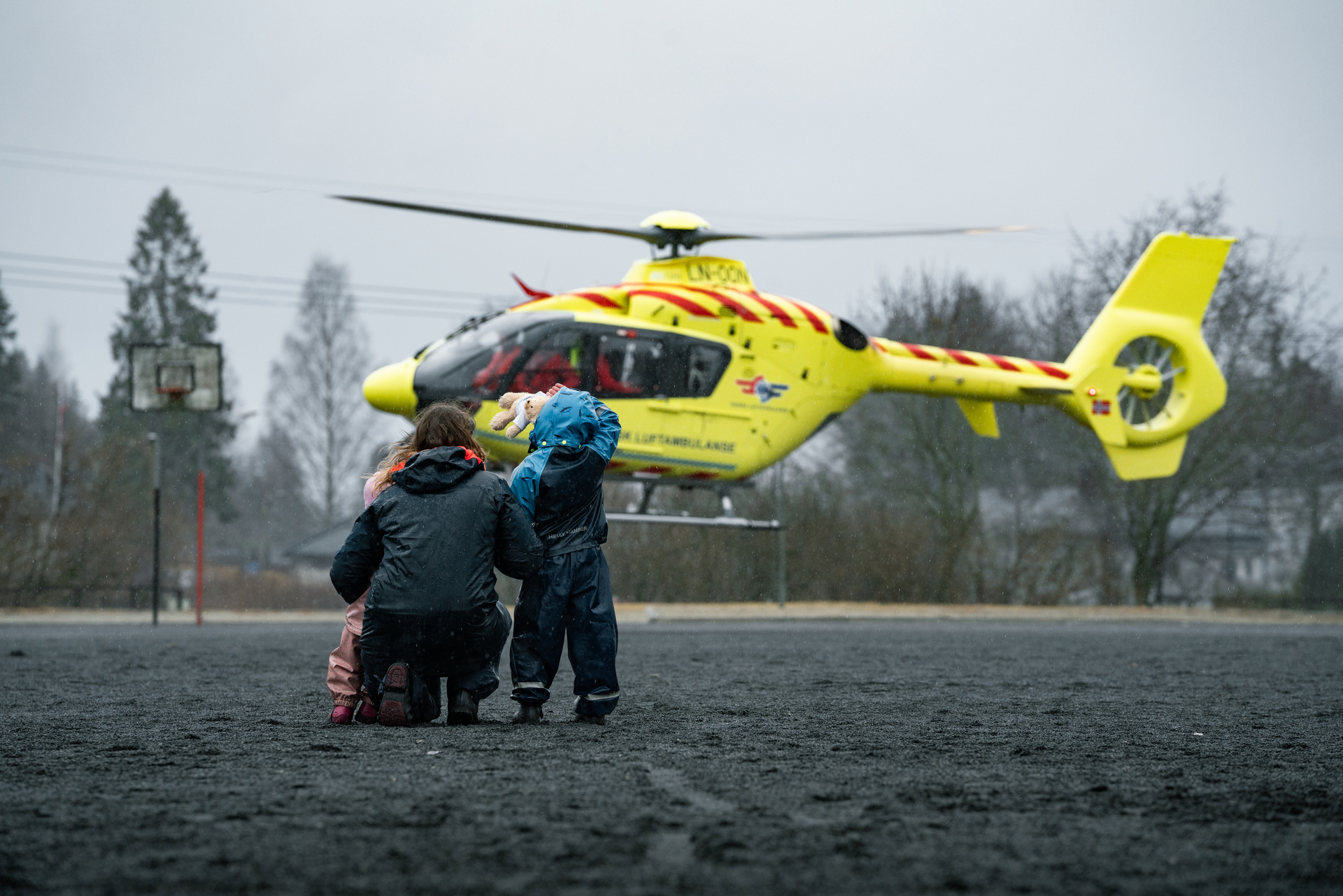 Mor holder rundt barna sine mens de ser helikopteret tar av