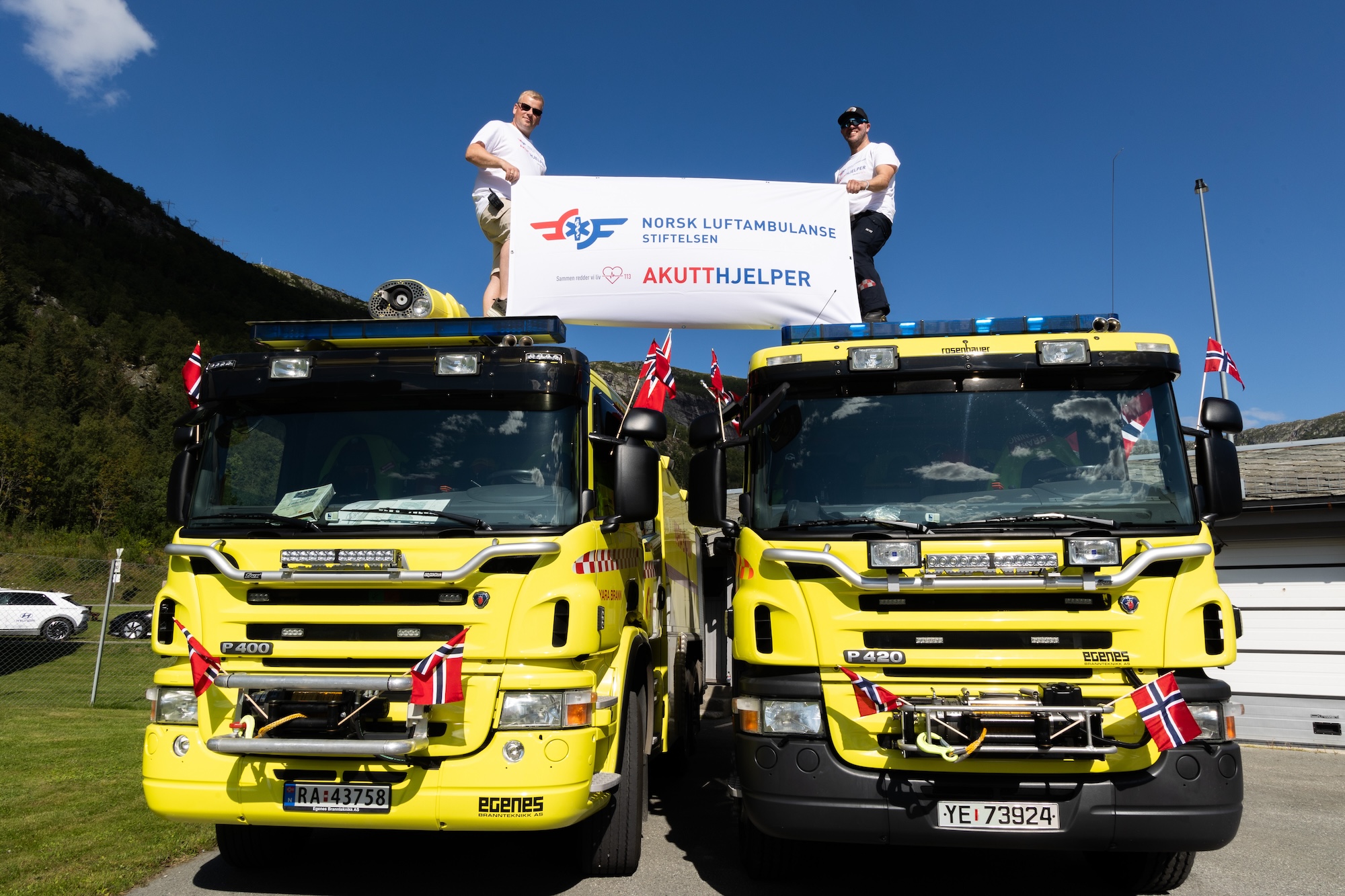 Akutthjelpere står på brannbilene med et banner