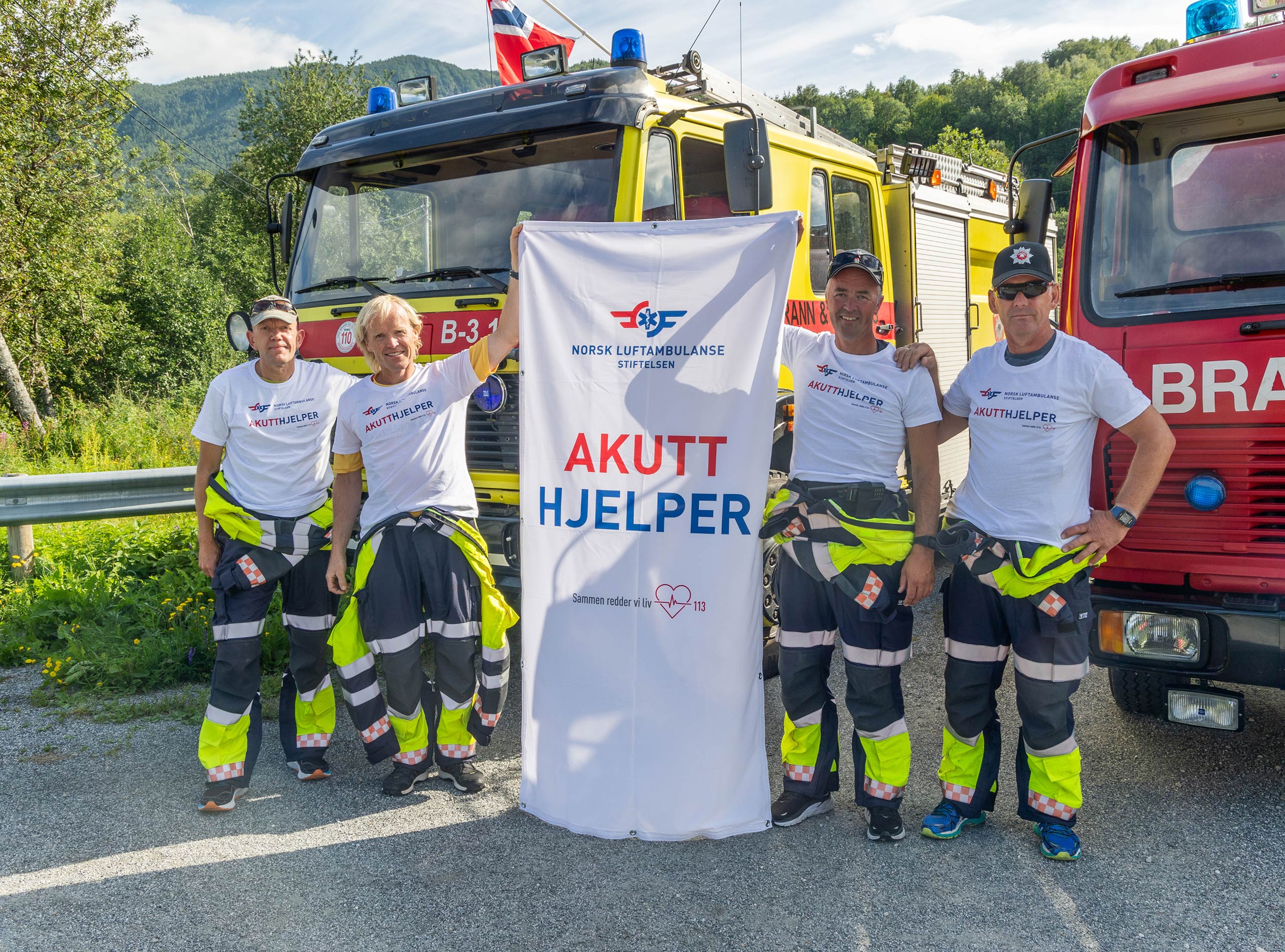Flere akutthjelpere holder oppe en banner med Akutthjelper-motiv.