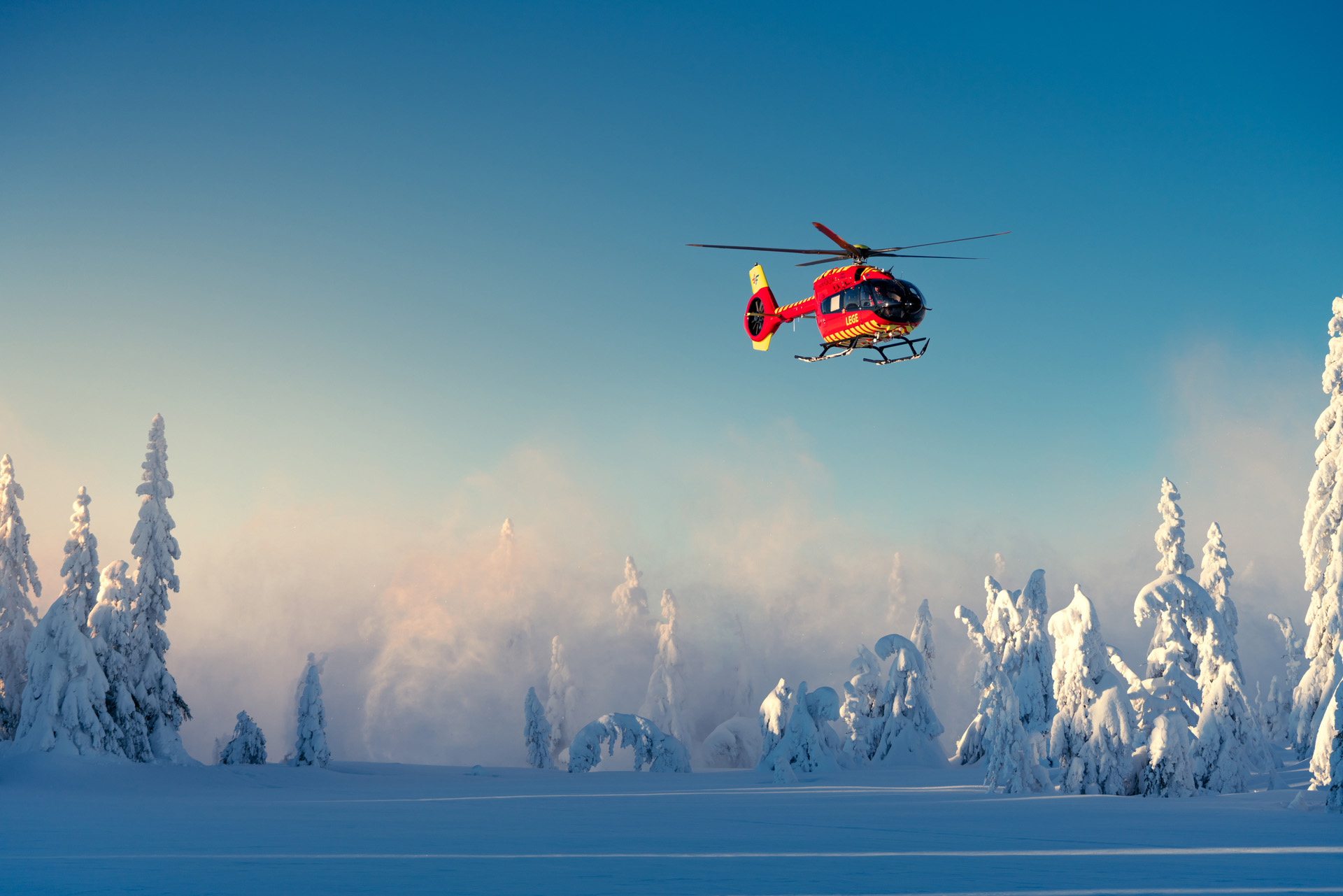 Helikopteret flyr over snødekt landskap