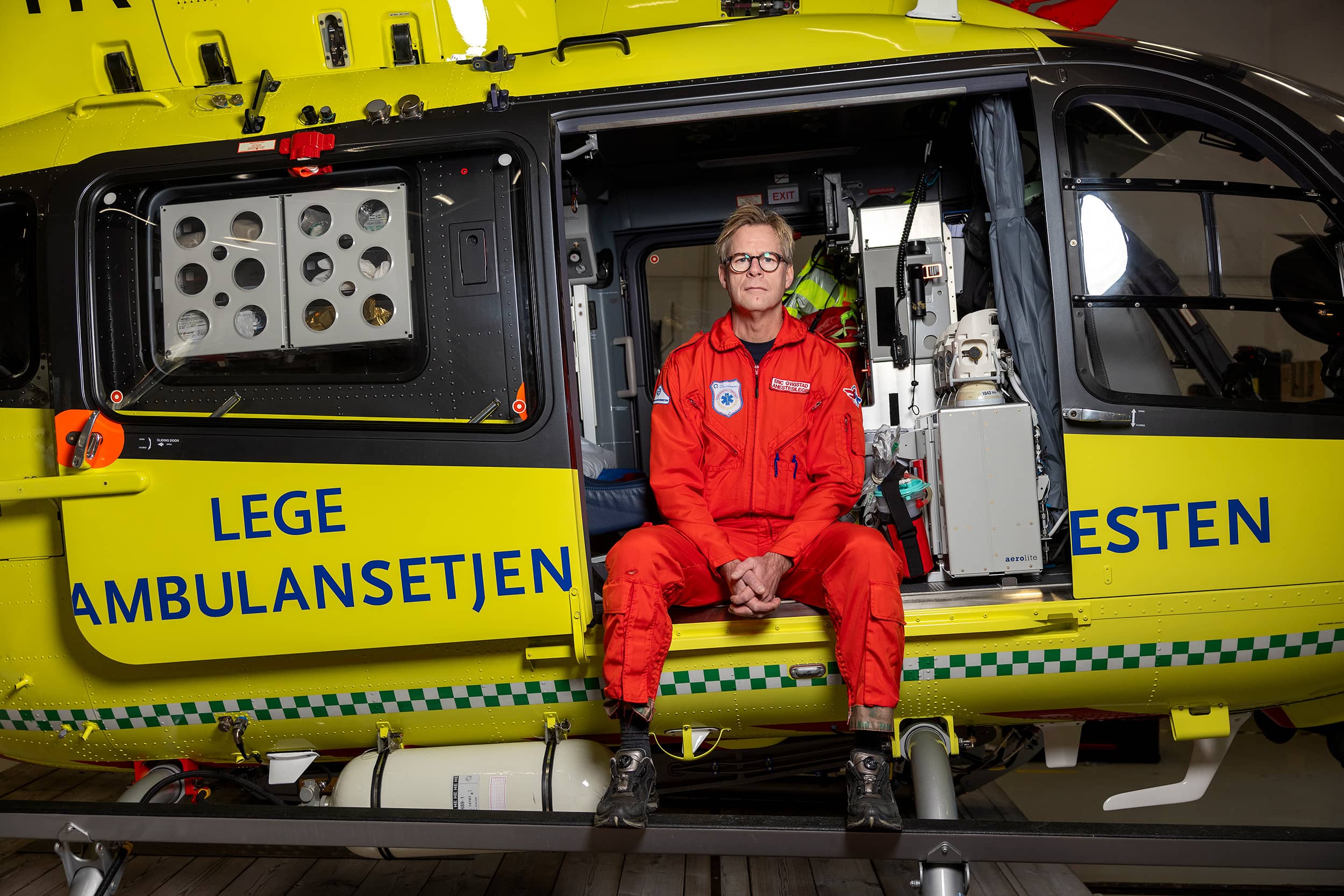 Portrett av luftambulanselege Eric Qvigstad foran legehelikopter