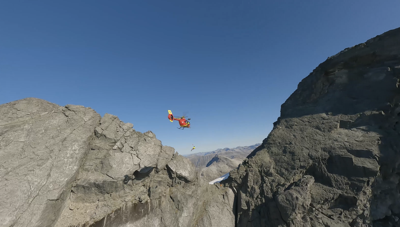 Redningsmann heises fra helikopter på et fjell