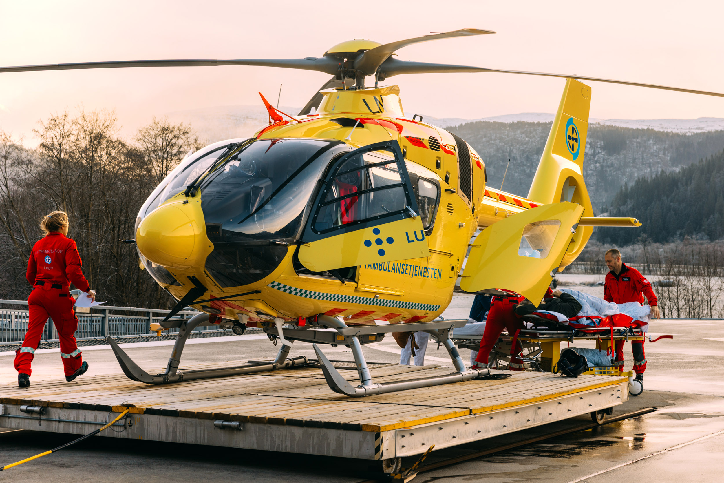 Gult legehelikopter landet på Førde-basen. Crewet har hentet en pasient som overleveres til Førde sentralsjukehus.