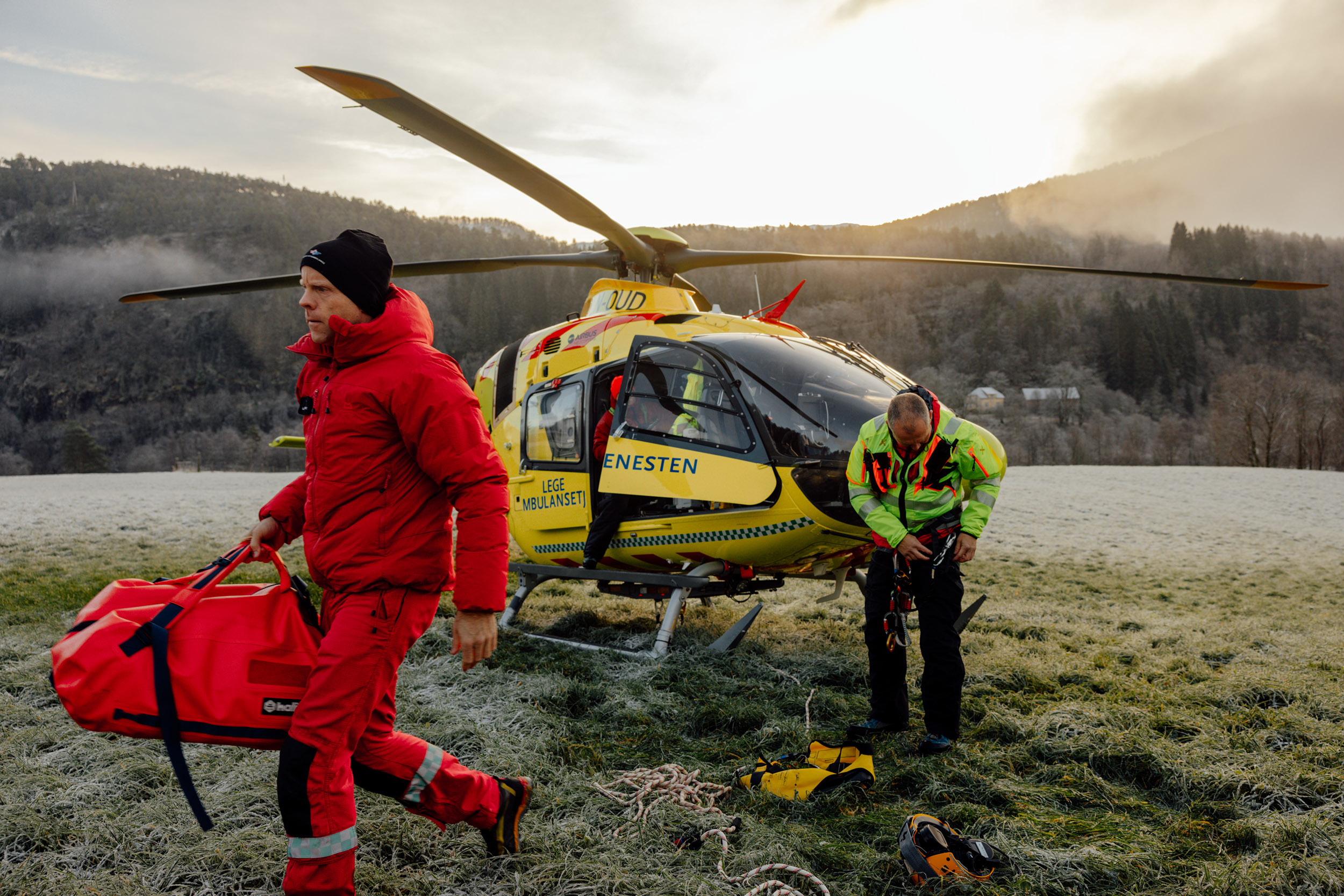 Pilot Kjell Ove Frøyset og redningsmann Anders Kroken utenfor legehelikopter parkert på en plen i. Førde. Mannskapet forbereder seg på trening i underhengende redning.