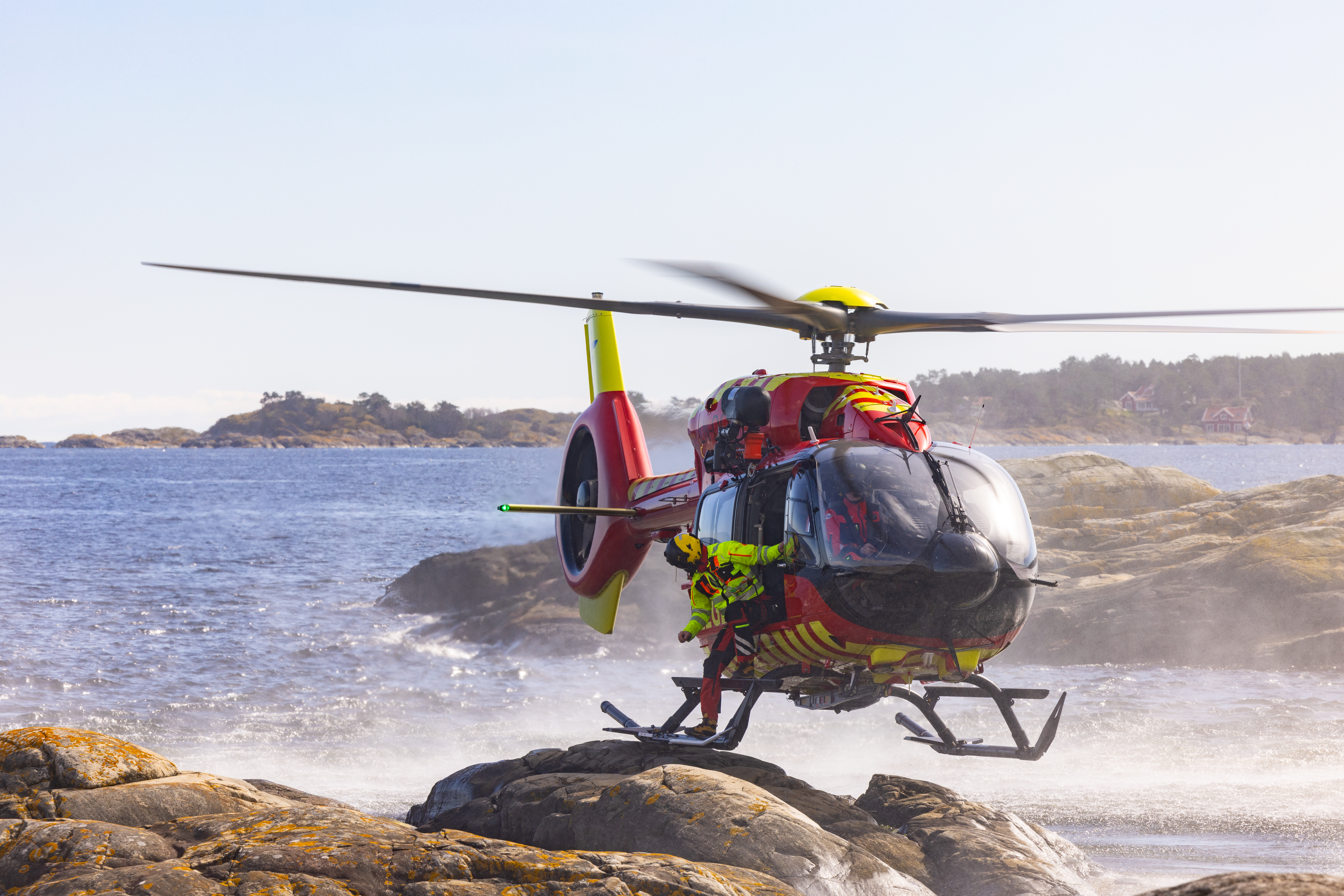 Helikopter som lander på svaberg og redningsmann er på vei til å gå ut