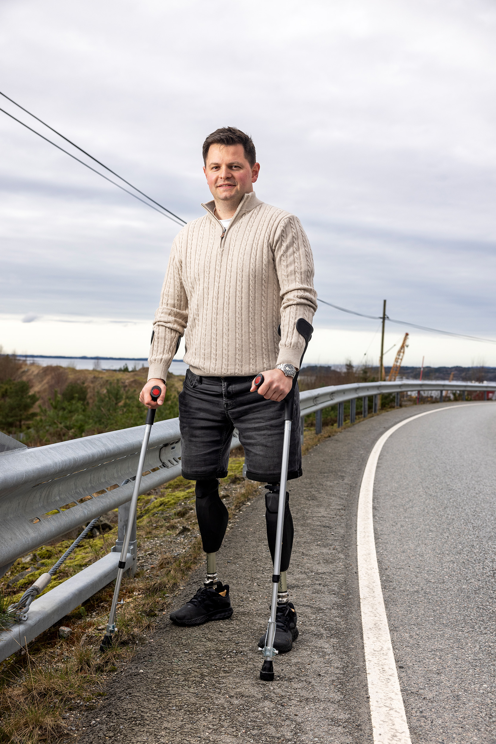 Portrett av Marcus der han står i veikanten med krykker og proteser på begge beina