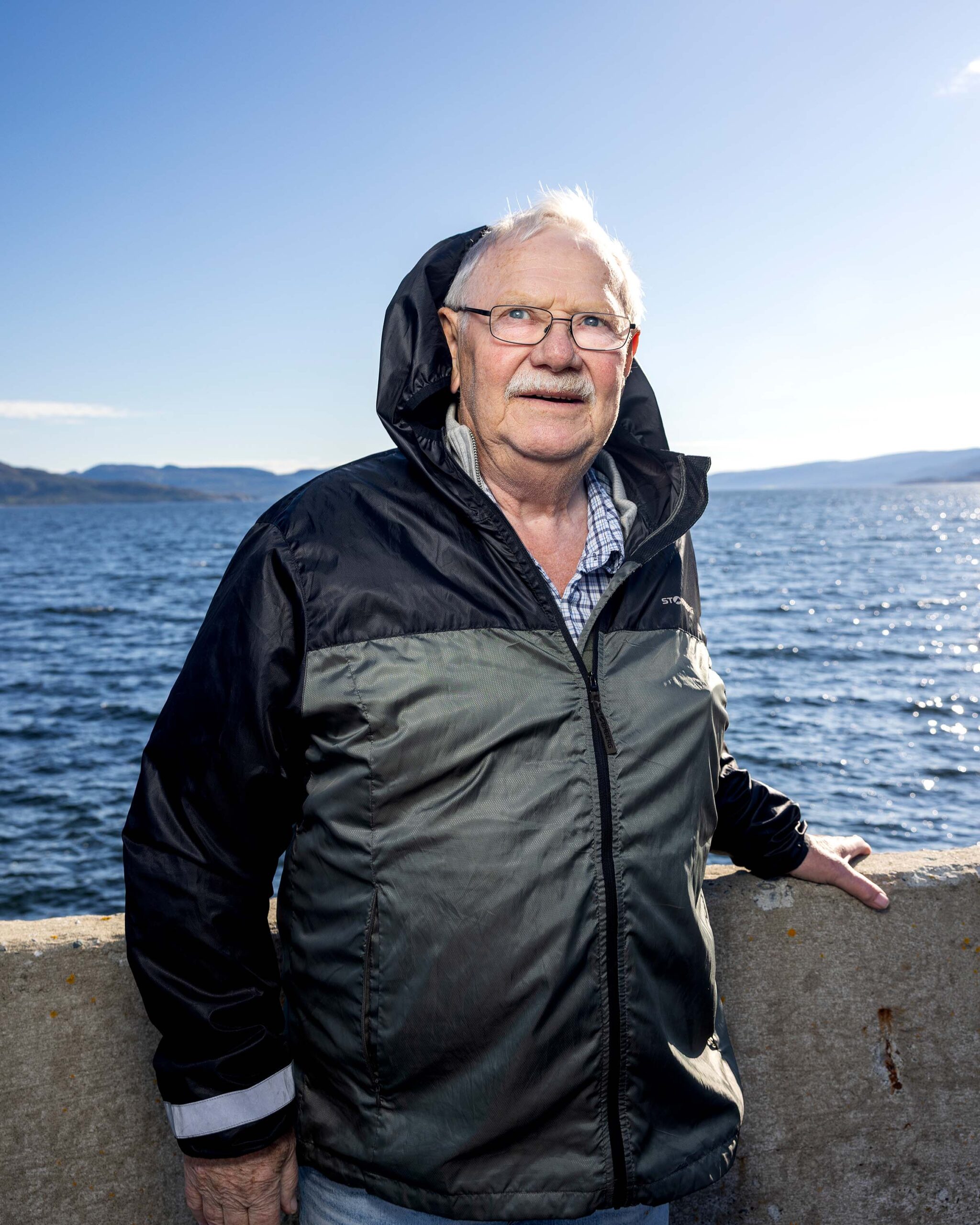 Mann står ved havna og ser inn i kamera