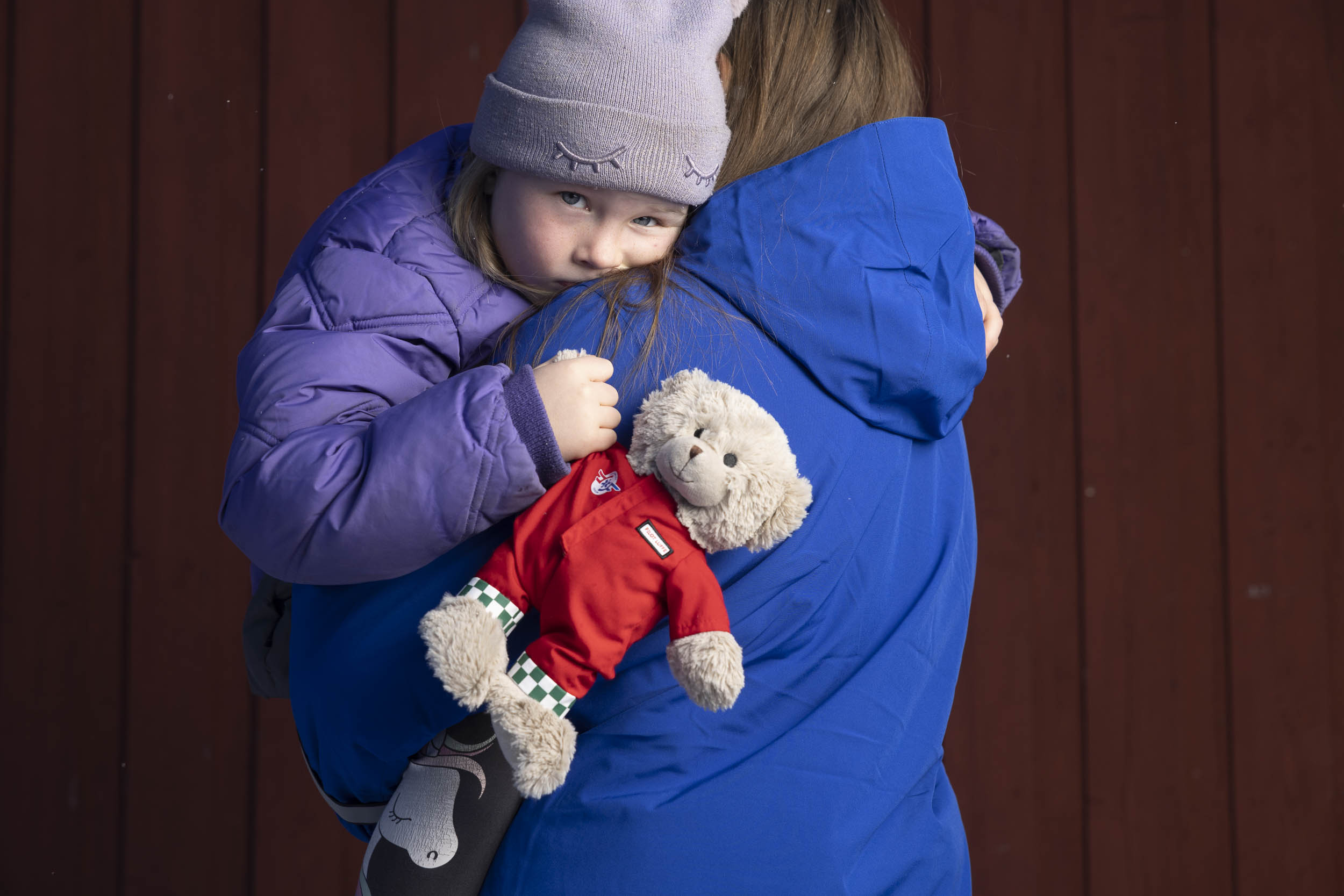 Datter i armene på mor mens hun holder Luffe-bamsen