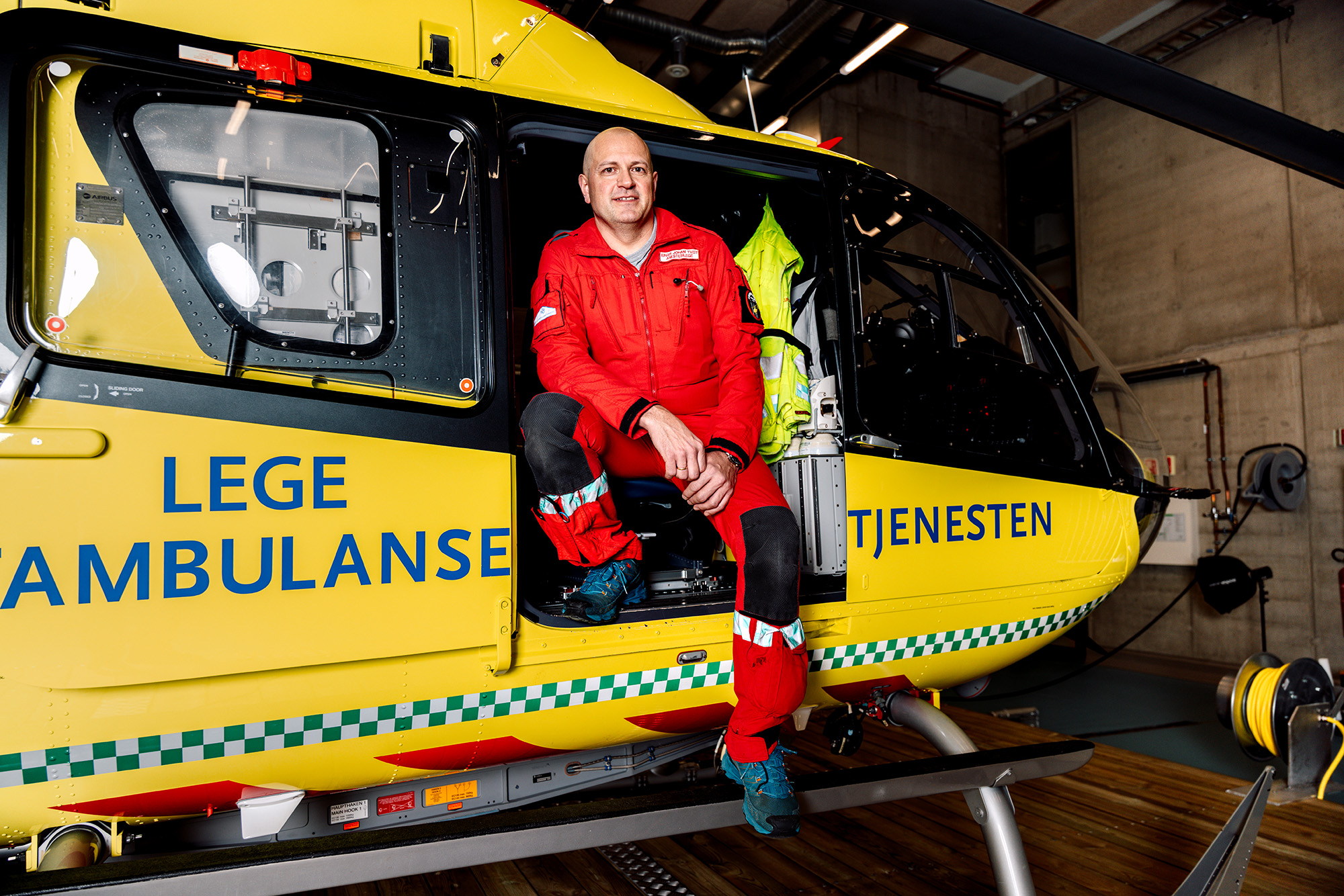Einar Johan Tveit sitter i døren til et gult legehelikopter