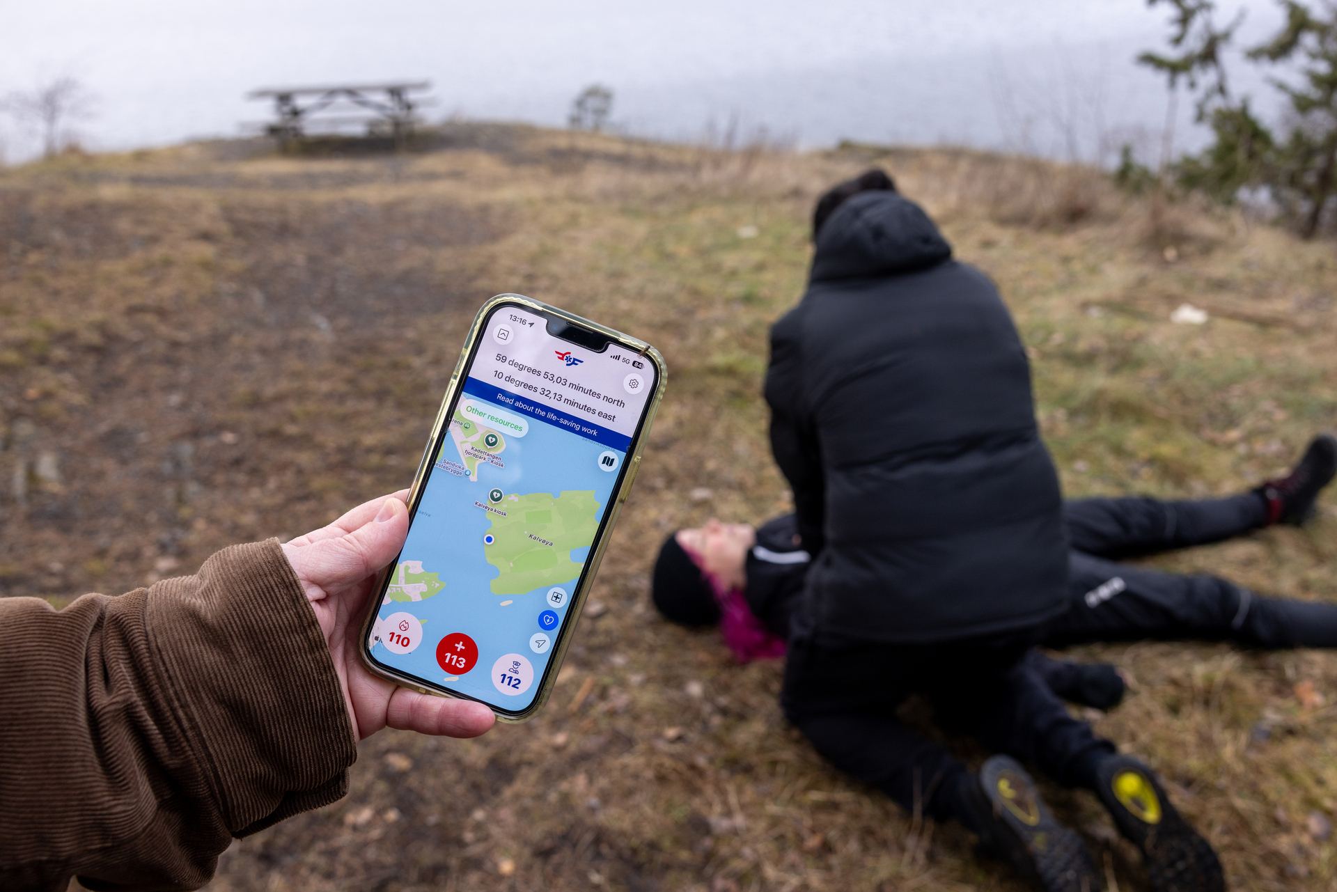 Kvinne har falt om på bakken og mann gjør livreddende tiltak