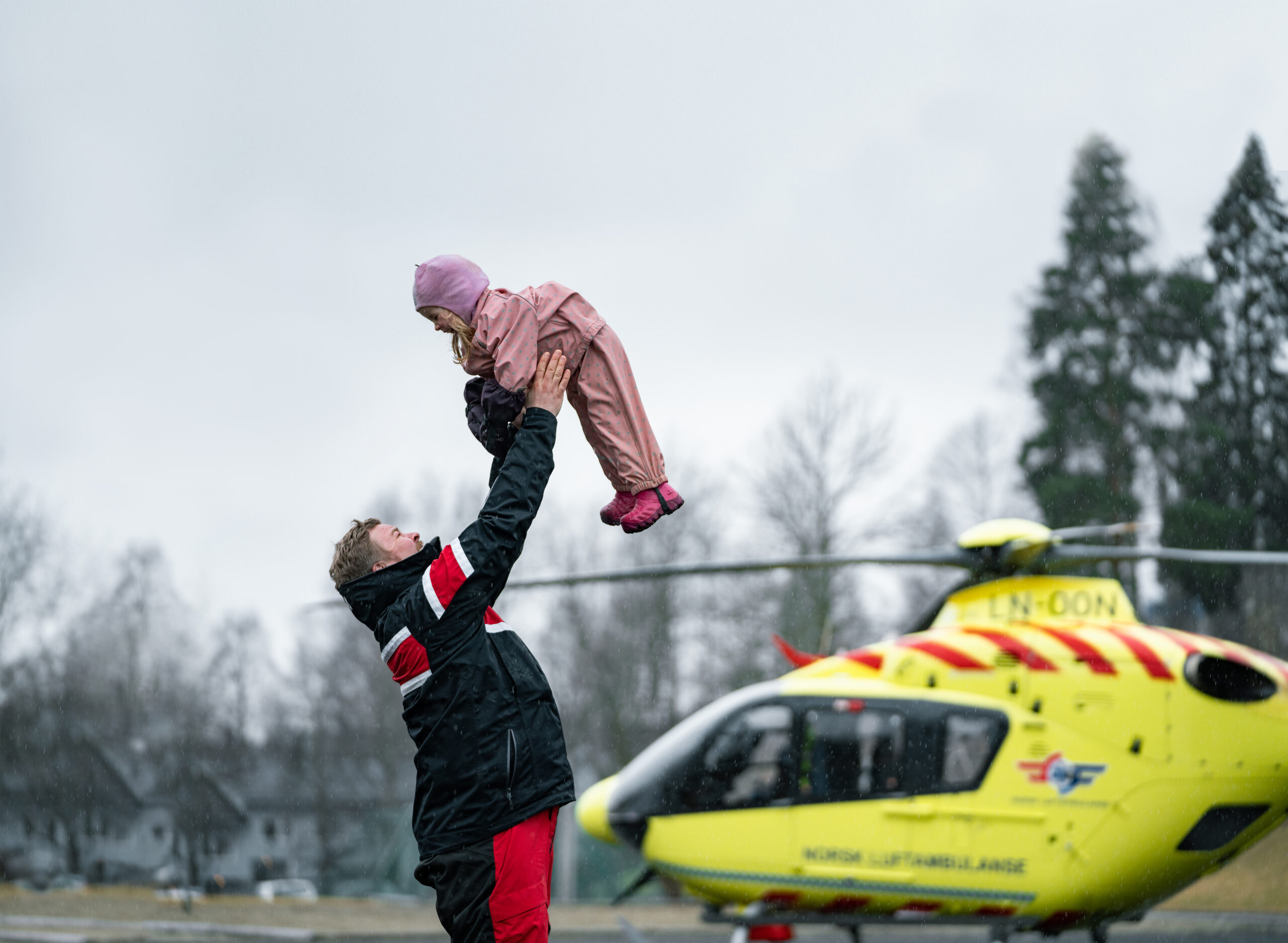 bilde av voksen og barn foran helikopter