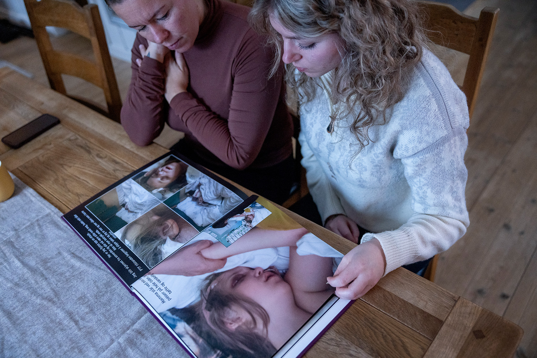 Tina og Alexandra blar i i et fotoalbum 