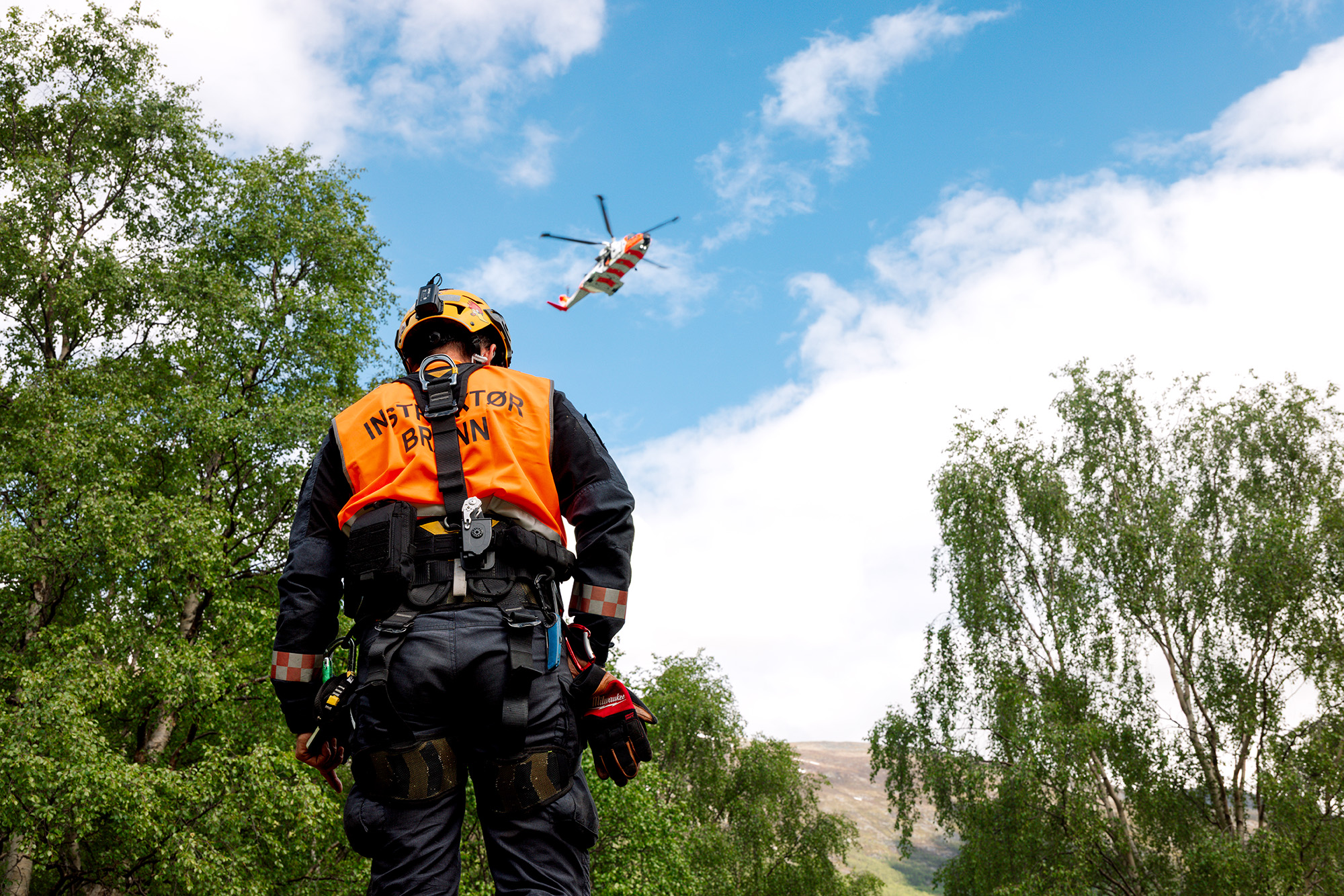 Instruktør fra brannvesenet i forgrunn, SAR Queen-helikopter i bakgrunn
