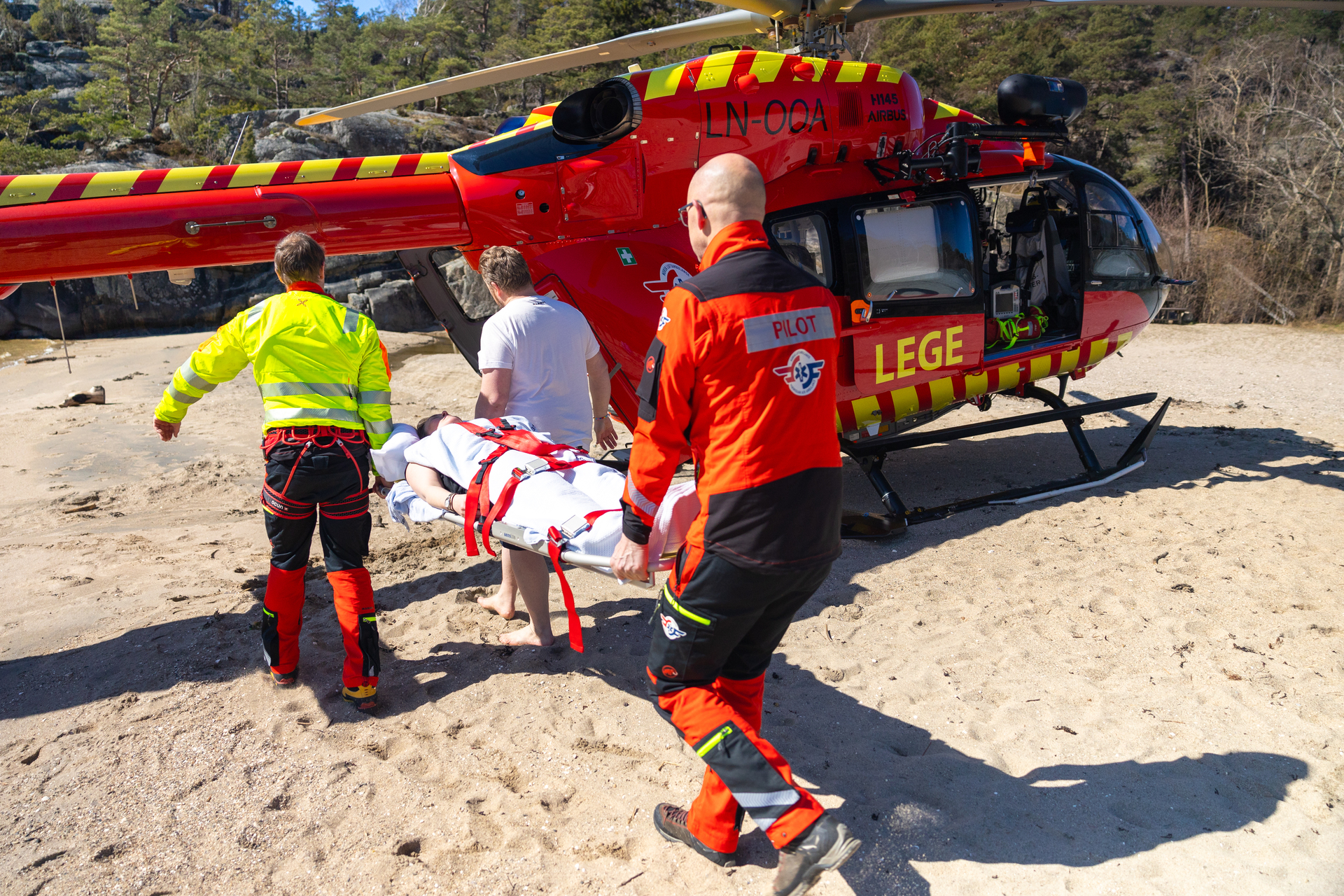 Crew og mann løfter pasient inn i helikopter